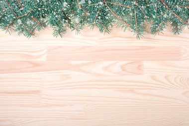 Noel ağacının köknar ağacıyla ahşap arka planı. Köknar dallı hafif ahşap zemin. Tebrik mesajı için yer var. Noel kartı. Üst Manzara. Kar taneleri etkisi. Karlı Ladin Dalları