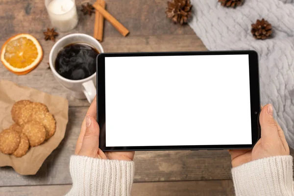 Mockup tablet. Woman shows blank white screen of digital tablet. Tablet in female hands. woman holds a tablet with a white screen at a table in a cafe. Top view. close-up