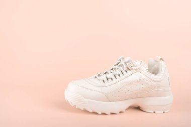Pastel arka planda izole edilmiş beyaz bir spor ayakkabı. Pembe arka planda yeni moda ayakkabılar. Spor ayakkabı konsepti. Boşluğu kopyala