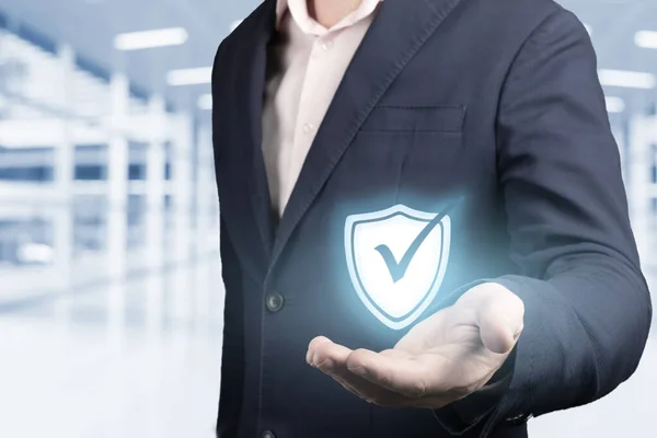business information security concept. businessman holds security symbol in hand. concept of cyber security, data protection, protection against hacker attacks and viruses. blurred office background