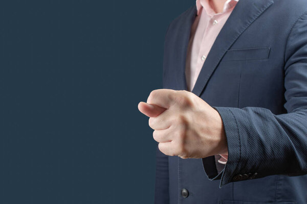 бизнесмен показывает фиговый жест. Бизнесмен в синем костюме показывает фиговый знак на синем фоне. жест презрения или отказ от концепции неприемлемых условий