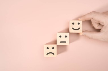 Müşteri, pembe arka planda mutlu bir ikon, simge suratlı ahşap küp bloğu, müşteri değerlendirmesi, memnuniyet araştırması konsepti ile en iyi iş hizmetleri değerlendirmesi derecesini gösteriyor..