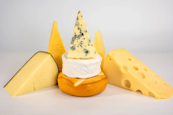 灰色の背景においしいチーズの異なる種類 ブルーチーズドルブ スモークスルグニ ブリー マサダム チェダー パルメザン 異なる種類のチーズの盛り合わせ — ストック写真