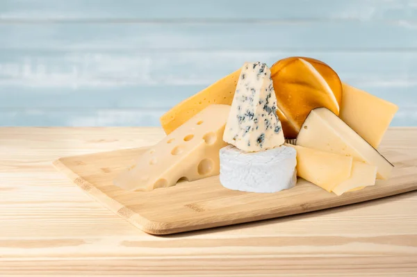 異なる種類のチーズが木の背景に含まれています ブルーチーズドルブ スモークスルグニ ブリー マサダム チェダー パルメザン 異なる種類のチーズの盛り合わせ — ストック写真