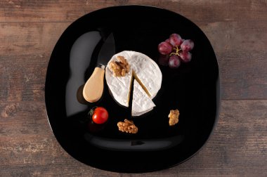 Siyah tabakta nefis brie peyniri. Ahşap kırsal masa. Brie peyniri. Camembert peyniri. Taze Brie peyniri ve taş tahtada bir dilim. İtalyan, Fransız peyniri.