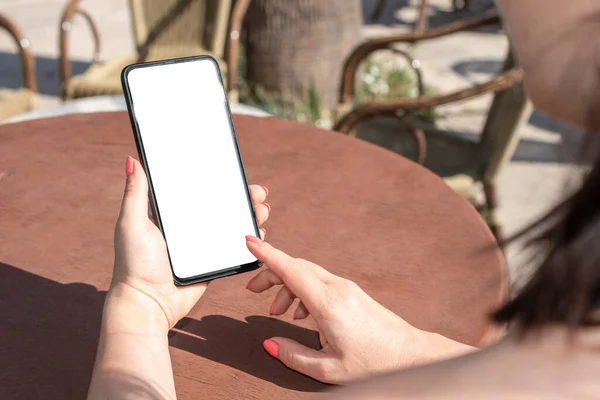 mockup phone. woman hold mobile cellphone with blank white screen at table in outdoor cafe. Woman Using Mobile Phone At Cafe
