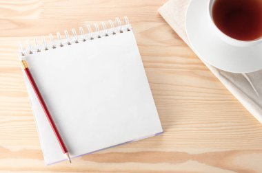 Kalem, defter ve çay fincanlarıyla ahşap masada boş bir not defteri. Açık Ahşap Arkaplan 'da boş çay fincanı ve kırmızı kalemle en üstteki görünüm defteri. Hayat, iş ya da eğitim kavramı.