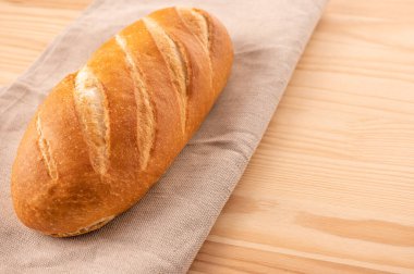 Tekstil peçetesi ahşap masa arkasına bir somun ekmek kapat. Ev yapımı ekmek. Ekmek tarifi. kopyalama alanı. Masada taze ekmek var.