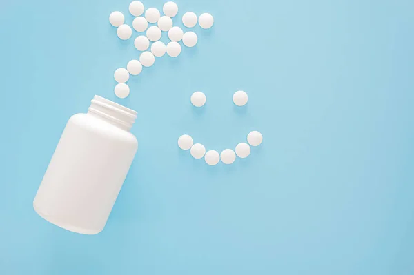 丸薬が並ぶ笑顔 白い瓶と散在する白い錠剤 青色の背景に白い丸薬から作られた笑顔 医学と医療の概念 最上階だ コピースペース — ストック写真