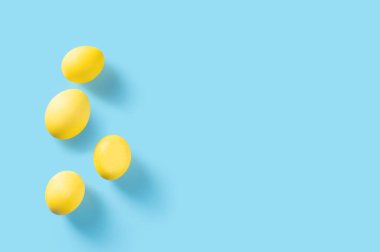 Mavi arka planda sarı paskalya yumurtaları. Güzel sarı yumurtalar mavi üzerine izole edilmiş ve kopyalama alanı var. Paskalya tebrik kartı. Mutlu Paskalyalar