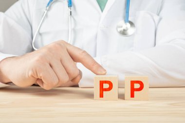 İnsanlar için gerekli vitaminler ve mineraller. Doktor PP vitamini almanı tavsiye ediyor. Doktor PP vitamininin faydalarından bahsediyor. PP Vitamin - Sağlık Konsepti. Tahta küpte PP alfabesi.