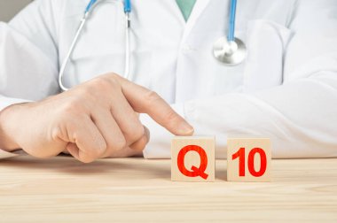 Koenzim Q10. İnsanlar için gerekli vitaminler ve mineraller. Doktor Q10 vitamini almanı tavsiye ediyor. Doktor Q10 vitamininin faydalarından bahsediyor. Vitamin - Sağlık Konsepti. Tahta küpte Q10 alfabesi.