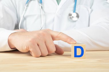 essential vitamins and minerals for humans. doctor recommends taking vitamin D. doctor talks about the benefits of vitamin D. D Vitamin - Health Concept. D alphabet on wood cube. clipart
