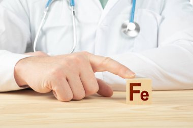 İnsanlar için temel element ve mineraller. Doktor Fe 'yi götürmemizi öneriyor. Doktor Demir 'in faydalarından bahsediyor. Ferrum - Sağlık Konsepti. Tahta küpte Fe alfabesi.