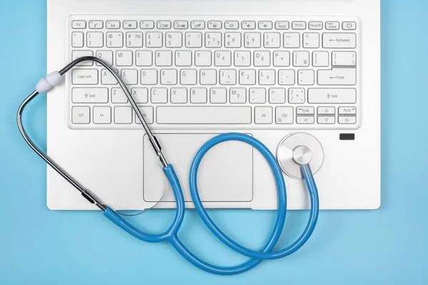 Online doctor consultation technology in laptop. Laptop, notebook pc with stethoscope on blue background. Healthy Hardware. Telemedicine concept. top view