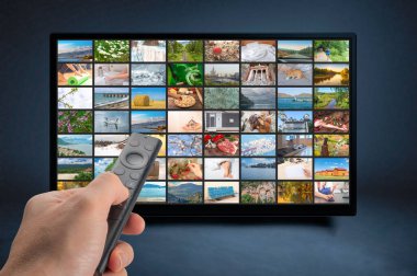 Erkek, uzaktan kumandayı tutuyor. Multimedya yayın konsepti. VoD içerik sağlayıcı konsepti. Televizyon yayını video konsepti. İnternet üzerinden yayın yapan multimedya şovları, serisi olan video servisi.