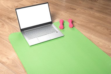 Çevrimiçi yoga fitness, dizüstü bilgisayar modeli. Pembe dambıllar, spor paspası ve ahşap zeminde gri dizüstü bilgisayar. Çevrimiçi egzersiz konsepti. kopyalama alanı. Laptop bilgisayarında çevrimiçi yoga dersi izliyorum..