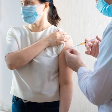 Aşı covid19. Doktor, Olgun Kadın 'a Covid aşısı yapıyor. Doktor kadın hastalara iğne yapıyor. Yüz maskesi takan kadın aşı oluyor, koronavirüs, covid-19 ve aşı konsepti..