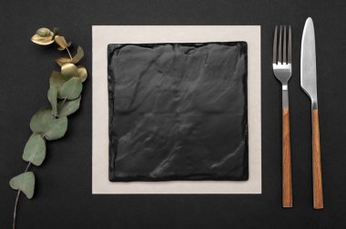Siyah tahta menü ya da tarif metni için çatal ve çatal. Ve siyah masanın üzerinde altın okaliptüs dalı. Siyah masa arka planında boş tahta ve çatal bıçak takımı
