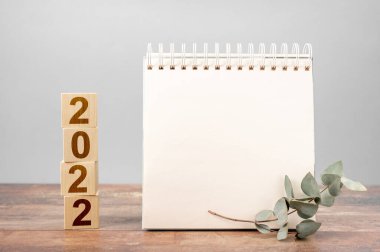 Yeni bir başlangıç için 2022 yılı. Kelime ve 2022 küp tahta masa arkaplanı planlayın. Yeni yıl. 2022 için planlar, not defterindeki metnin için boşluk, model takvimi