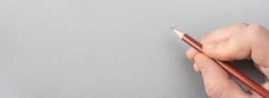 Gri kağıda kalemle yazmak. Gri kağıda bir şeyler yazan bir el. Boş kağıt şablonuna kurşun kalemle insan eli çizimi. Metnin, mesajın ve bağlantıların için boşluk