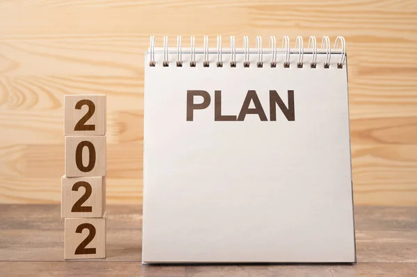 2022 time for a new start. Plan words and 2022 cubes wooden table background. New Year. plans for 2022, space for your text on notepad, mockup