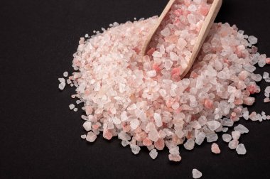 Pembe Himalaya tuzu. Himalaya Pembe Kaya Tuzu, tahta kaşıkla siyah arka planda. Üst Manzara. Yüksek açılı Himalaya Tuzu Masada Tahta Kaşıklı