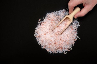 Pembe Himalaya tuzu. Himalaya Pembe Kaya Tuzu, tahta kaşıkla siyah arka planda. Üst görünüm, boşluğu kopyala. Pembe himalaya tuzlu ahşap kaşık.