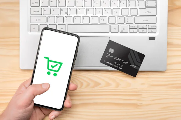 online shopping, phone laptop and credit card. Top view man at wooden desk with mockup phone , credit card and laptop. person makes a purchase online
