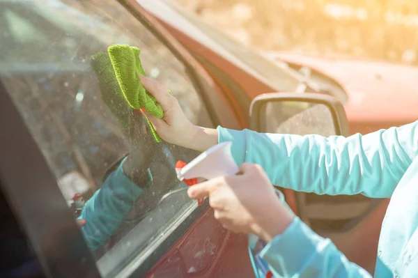 car windows cleaning. female cleaning car windshield with cloth and spray bottle. Closeup picture, woman, driver, dry wiping her car with microfiber cloth, cleaning auto, automobile windows