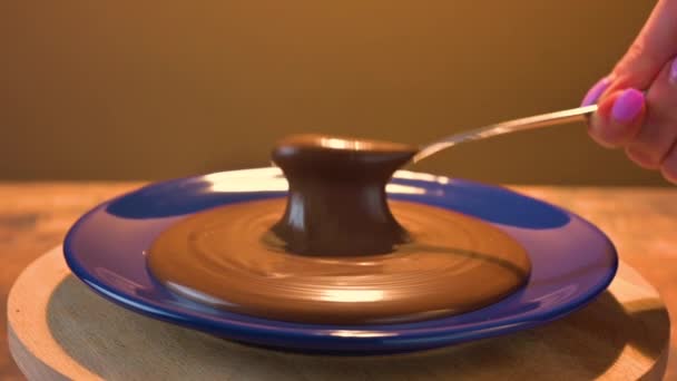巧克力用勺子铺在旋转的蓝色盘子上 女性的手与一汤匙巧克力糊 慢动作 褐色背景 — 图库视频影像
