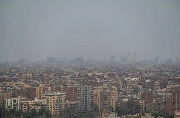 View on the city of Giza in a morning with smog, outskirts of Cairo, as seen from the Giza Plateau. aerial view of misty of city of Cairo in Egypt, due to traffic pollution, over rooftop slums