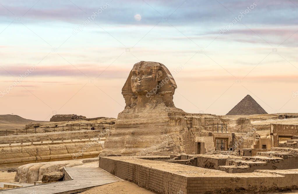 Egyptian Great Sphinx full body portrait with head, feet with all pyramids of Menkaure, Khafre, Khufu in background on a clear, blue sky day in Giza, Egypt, View of sphinx, giza plateau in desert