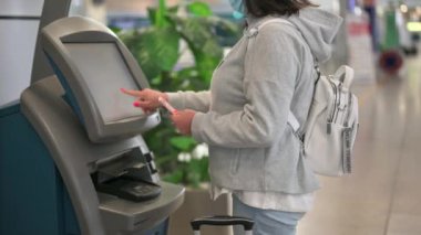 Havaalanında kendini kontrol eden bir kadın. Kadın havaalanında kendini kontrol eden bir büfeye giriş yapmış. Coronavirüs salgınından sonra hava yolculuğu açılıyor.