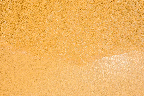 wet sand texture. Small wave of water on clear sandy beach. Sand beach and wave. Golden sand texture, top view