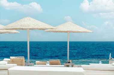 Otel tatil köyünün plajı, plaj şemsiyeleri ve güzel denizin arka planına karşı güneş panelleri. Boş sahil yaz arkaplanı. tatil kavramı