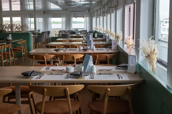 Capture the interior view of the restaurant at the cruise ship. row of tables in a small cruise ship restaurant. panoramic windows