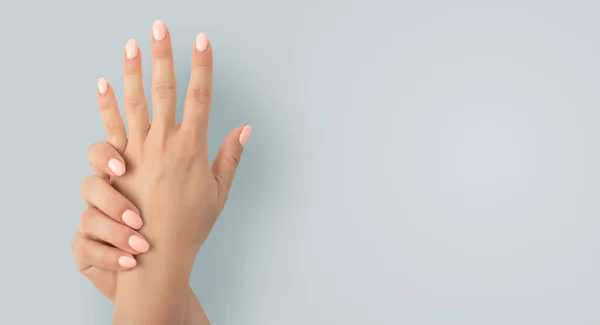 Beautiful female hands with stylish nail manicure gel polish on gray background. Closeup view of woman with beautiful hands on grey background, space for text. Spa treatment, manicure