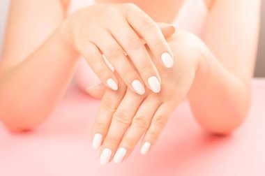 Yetişkin bir kadının güzel ve bakımlı elleri. Orta yaşlı kadın ayası. Hijyen ve el bakımı. Güzellik endüstrisi konsepti. Güzellik salonunda profesyonel manikür. pembe tablo