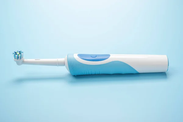 modern electric toothbrush lies on blue background. Dental care tools on white background. concept of good mouth hygiene. Electric toothbrush, close-up.