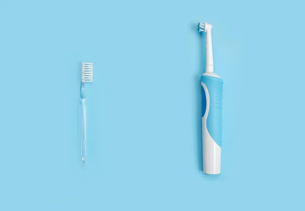 Traditional Manual and Electric Toothbrush Over Blue. choice between electric and classic toothbrush on blue background. Manual Regular Toothbrush Against Modern Electric Toothbrush. copy space