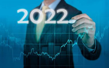 Takım elbiseli bir iş adamı. Analiz planı kâr tablosu. 2022 iş adamı için ekonomik tahminler sanal ekranda 2022 yazıyor. Ekonomik iyileşme ardından covid 19 koronavirüs salgını