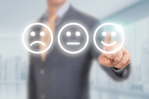 Businessman pressing excellent smiley face rating icon over light blue background, customer service evaluation and feedback rating concept. costumer review concept, man pointing on happy smiling face