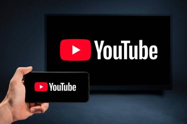 MOSCOW, RUSSIA - 25 Ağustos 2021: Telefon ve TV ekranında internet servisi Youtube. Video sunuculuğu sitesi. Youtube TV logosu olan bir cep telefonu tutan adamları kapat
