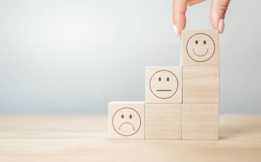 Müşteri hizmetleri ve memnuniyet konsepti. İnsanlar gülen tahta küplü gülen yüz ikonu ile geri bildirim göstererek hizmette tatmin oluyorlar. reyting çok etkileyici.