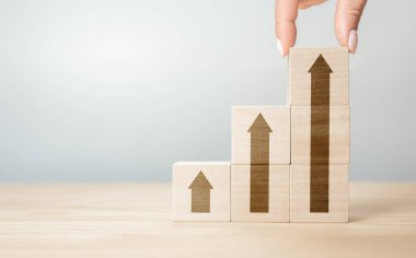 Elle düzenleme tahta bloğu ve ok simgesi. Tahta blokları masanın üzerine istifleyen insan eli. İş kavramı büyüme başarı süreci