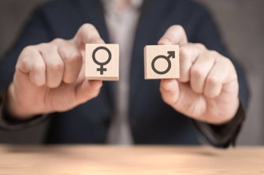 choice between man and woman. hands hold two wooden cubes with Gender icon, male and female sign. equality and differences between men and women. choice of woman or man for leadership post clipart