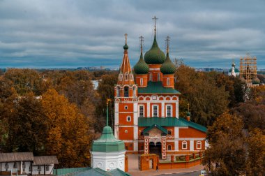 Sonbahar, sonbahar yapraklarının arka planında altın kubbeler olan Hıristiyan kilisesi. bulutlu sonbahar gökyüzü. Rusya 'da sonbahar. Sonbahar havasında kilise.
