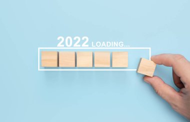 Yeni yıl 2022 'yi elle yüklemek, odun küpünü ilerleme çubuğuna koymak. Yeni yıl 2022 yükleniyor. Mutlu Noeller ve mutlu yıllar iş dünyası konsepti