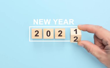 Yeni yıl 2021 'den 2022' ye geçiş. Tahta bloğu elle ters çevir. Tahta küplerin 2021 'den 2022' ye çevrilmesi. Mutlu Noeller ve mutlu yıllar konsepti.